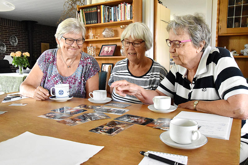 Snakken går livligt hen over kaffebordet hos Erna Kristensen, mens Tove Pedersen (t.v.), Erna Kristensen og Grethe Moesner ser på billeder fra 40 år med Hjerting Folkedansere.
